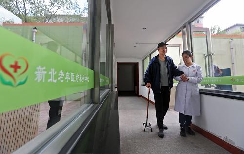 4月21日,养护中心护士何骥搀扶一位老人散步回来。新华社记者 姚剑锋 摄