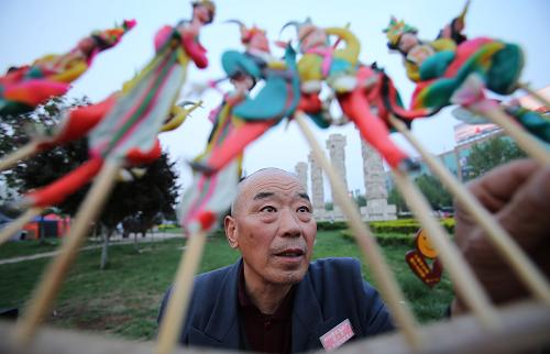 4月21日,董金龙在街头现捏现卖他的面塑作品。新华社发(鲍东升 摄)