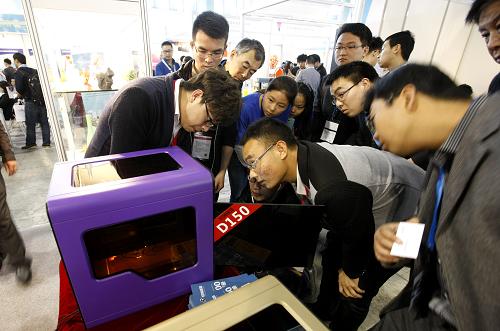 4月24日,观众在参观一台正在进行打印演示的3D打印机。新华社记者 方喆 摄