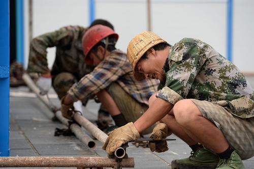 6月2日,施工人员在盈江县第一中学铺架板房外的防晒网。新华社发(胡超 摄)