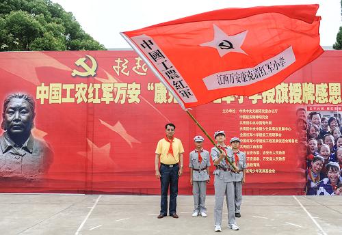 6月3日,康克清红军小学的学生代表在授旗授牌仪式上挥舞校旗。当日,全国红军小学建设工程理事会在江西万安举行康克清红军小学授旗授牌仪式。仪式上,社会各界人士向学校捐赠了电教设备、文化用品等来改善红军小学的教学条件。新华社记者 李琰 摄