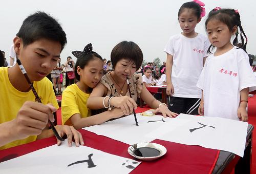 6月15日,志愿者在指导夏令营的东干少年书写汉字。当日,来自俄罗斯、吉尔吉斯斯坦、哈萨克斯坦的40余名“2014中国寻根之旅夏令营—西安营(中亚东干营)”成员与西安高新第二学校的师生们齐聚西安汉城湖,拜孔子、习书法、吟诵《弟子规》,体验中国传统文化。东干人主要分布在中亚的哈萨克斯坦、吉尔吉斯斯坦及乌兹别克斯坦,其中一半是130多年前由陕西迁居中亚的陕西后裔,100多年来,东干人的语言及习俗依旧保留着清朝中后期陕西风貌。新华社记者 刘潇 摄