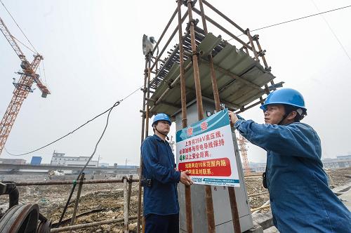 6月18日,电力工作人员在一处工地悬挂警示标志。新华社记者 徐昱 摄