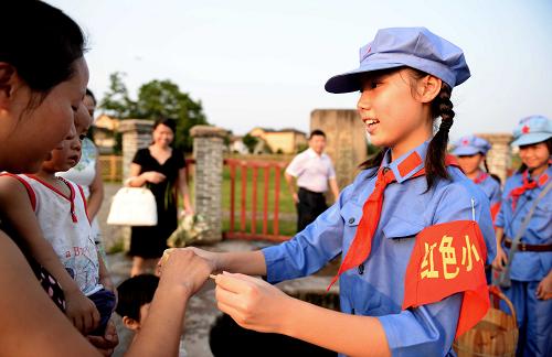 身着红军服装的“小导游”在瑞金市红井景区为游客送上红井井水。瑞金市每年都有中小学生利用假期来到红色景区为游客进行义务讲解(8月1日摄)。新华社记者 陈子夏 摄