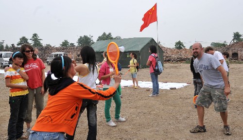 5月31日,天河海军小学的一名学生在操场上与加拿大的志愿者打羽毛球。 “六一”儿童节来临之际,四川省绵竹市东北镇天河海军小学的学生以积极乐观的态度迎接自己的节日。 新华社记者 郝同前摄