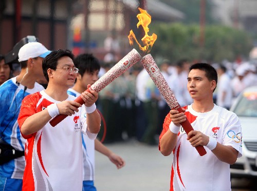 6月14日,火炬手桂阳(右)与下一棒火炬手王进江交接。当日,北京奥运火炬传递活动在贵州省遵义市举行。 新华社记者邢广利摄