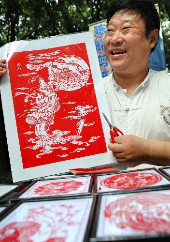 9月13日,南京剪纸艺人陈耀向游人介绍他的剪纸作品“嫦娥奔月”。新华社记者 孙参 摄