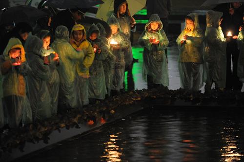 12月12日,参加仪式的小学生代表冒雨点燃手中的红烛。新华社记者 韩瑜庆 摄