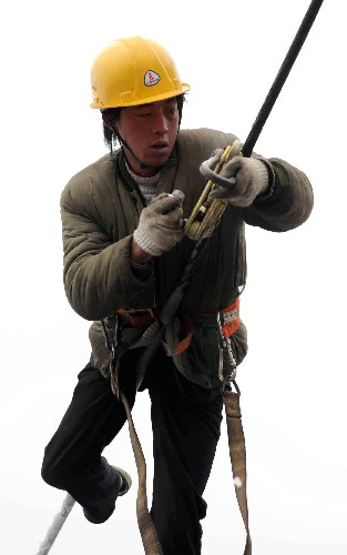 2月2日,在贵阳市图云关的一条因雪凝灾害造成的110千伏输电线路的损毁现场,南方电网公司贵州送变电的一位抢险人员正在高空架最后一相电。 新华社记者 杨楹 摄
