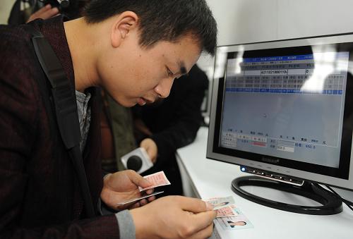 1月21日,一名旅客在深圳火车北站购票窗口核实自己买到的实名制火车票。新华社记者 卢汉欣 摄