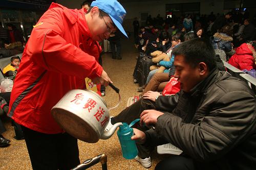 1月30日,一名志愿者在济南火车站为旅客送开水。一年一度的春运又在紧张和繁忙中拉开了帷幕,返乡的人们都盼早日踏上归途,而身处春运服务一线的工作者和志愿者为保证春运平安有序依然坚守岗位,默默奉献。新华社发(吕传泉 摄)