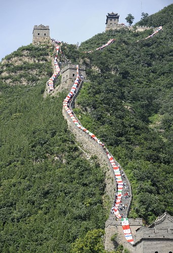 这是“奥运龙”在居庸关长城上“腾飞”(7月13日摄)。7月13日是北京申奥成功七周年纪念日,一幅长度超过万米的“奥运龙”巨幅画卷在北京居庸关长城“腾飞”,以展现全球华人对北京奥运会的支持。“奥运龙”作品以中国龙为主体,全长13112米,以奥运五环色彩为基色制作,由参与北京奥运会的205个国家和地区的国旗、区旗以及200多种文字祝福北京奥运会、祝福世界和平的图案组成。“奥运龙”龙头高达6.6米,活动后将捐赠给中华思源扶贫基金会永久收藏,以支持公益事业。 新华社记者 戴旭明 摄