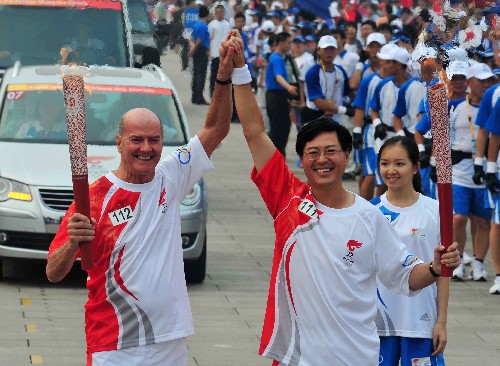 8月6日,火炬手杨元庆(右)与下一棒火炬手高斯帕(Gosper Richard kevan)交接后庆祝。当日,北京奥运圣火在北京市传递。 新华社记者安治平摄