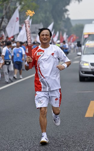 8月6日,火炬手何宁手持火炬传递。当日,北京奥运圣火在北京市传递。 新华社记者戚恒摄