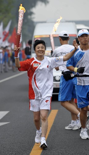 8月6日,火炬手李春玲手持火炬传递。当日,北京奥运圣火在北京市传递。 新华社记者戚恒摄