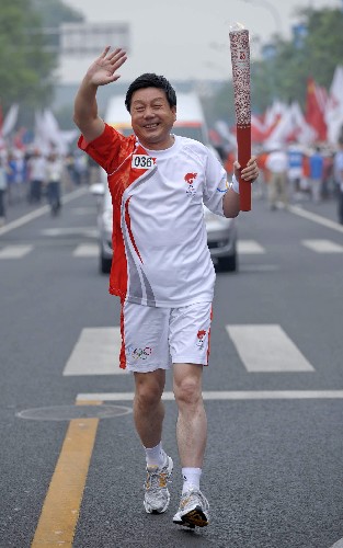 8月6日,火炬手骆京手持火炬传递。当日,北京奥运圣火在北京市传递。 新华社记者戚恒摄