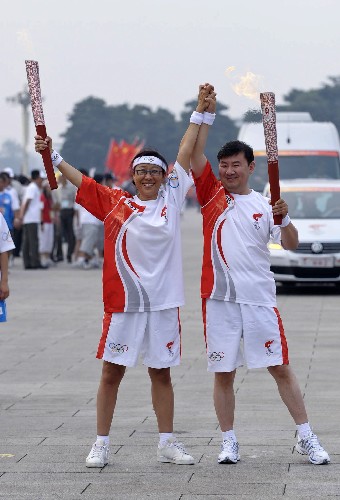 8月6日,火炬手马一德(右)与下一棒火炬手陈麒亦交接后庆祝。当日,北京奥运圣火在北京市传递。 新华社记者戚恒摄