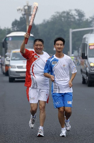 8月6日,火炬手李伟洪手持火炬传递。当日,北京奥运圣火在北京市传递。 新华社记者戚恒摄
