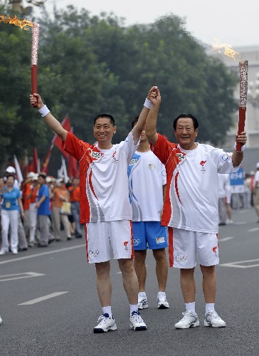 8月6日,火炬手张百发(右)与下一棒火炬手左芷津交接后庆祝。当日,北京奥运圣火在北京市传递。 新华社记者戚恒摄