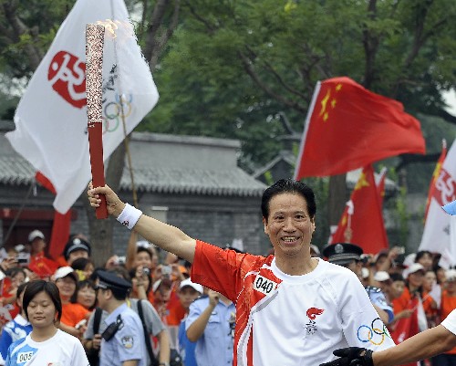 8月6日,火炬手、北京奥运会国家摄影队领队、新华社摄影部主任徐祖根手持火炬传递。当日,北京奥运圣火在北京市传递。 新华社记者戚恒摄