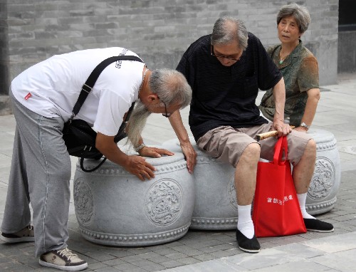 8月7日,几位老人在前门大街参观时研究起石墩凳子。当日,北京前门大街正式开街。北京前门大街北起前门月亮湾,南至珠市口,全长840米。自2007年5月9日开始,前门大街开始了大规模修缮整治工程。此前的几年里,修缮方案共经过了16位文物专家32次专业论证。 新华社记者张燕辉摄