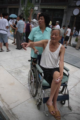 8月7日,一位老人坐着轮椅在前门大街参观。当日,北京前门大街正式开街。北京前门大街北起前门月亮湾,南至珠市口,全长840米。自2007年5月9日开始,前门大街开始了大规模修缮整治工程。此前的几年里,修缮方案共经过了16位文物专家32次专业论证。 新华社记者张燕辉摄