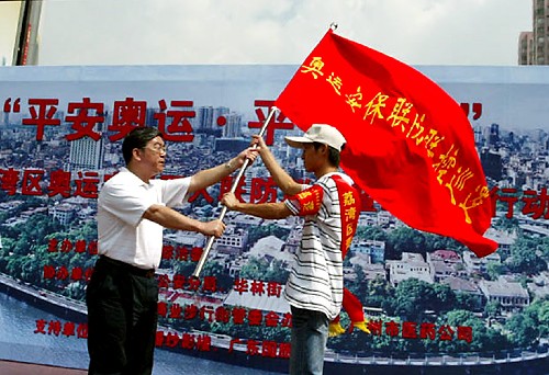 8月1日,广州市荔湾区的有关负责人(左)将队旗交给奥运安保志愿者行动队的代表。