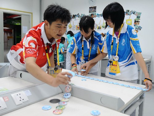 小标识 大作用 8月12日,参与志愿者岗位标识徽章设计的任炜、吴雪杨、于婧(从左至右)等在整理志愿者岗位标识徽章。 北京奥运会羽毛球赛目前正在北京工业大学体育馆紧张进行,场上队员们在挥拍奋战,场下的志愿者们也在各个岗位忙碌。据北京工业大学体育馆志愿者经理任炜介绍,此次服务北京奥运会北京工业大学场馆的志愿者一共有1170名,分布在20余个业务口中,为了区分岗位和激励志愿者,他们首创了志愿者岗位标识并制成徽章。根据服务范围和对象的不同,业务标识各不相同,为向志愿者寻求帮助的人提供了直观的依据,也增强了志愿者的责任感和自豪感。 新华社记者罗晓光摄