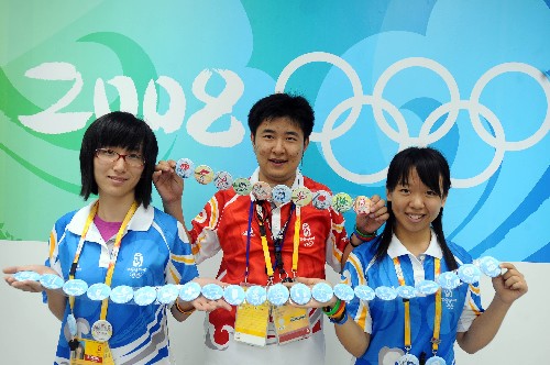 8月12日,参与志愿者岗位标识徽章设计的于婧(左)、任炜(中)、吴雪杨在展示志愿者岗位标识徽章。