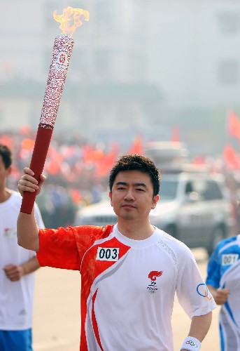 5月16日,奥运火炬手芮成钢手持火炬进行传递。当日,北京奥运圣火传递活动在江西南昌举行。 新华社记者 邢广利 摄