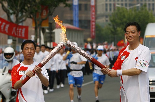 5月23日,火炬手沈富麟(右)与火炬手周建明交接。当日,北京奥运会圣火在上海传递。 新华社记者 凡军 摄