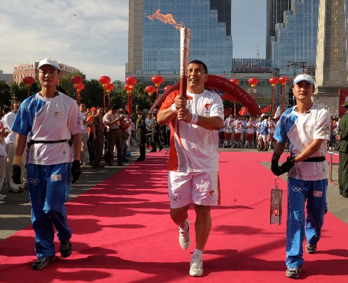 6月17日,火炬手米吉提阿不都西库(中)手持火炬传递。当日,北京奥运圣火在新疆乌鲁木齐传递。新华社记者 赵戈 摄