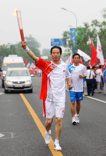 8月6日,火炬手、北京奥运会国家摄影队领队、新华社摄影部主任徐祖根手持火炬传递。当日,北京奥运圣火在北京市传递。 新华社记者 邢广利 摄