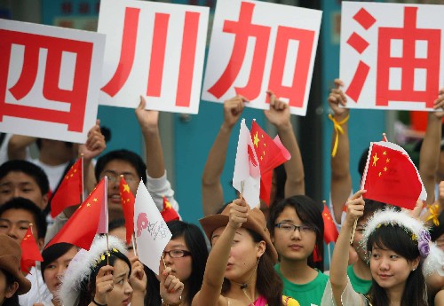 5月24日,群众在观看火炬传递活动时打出“四川加油”的标语。当日,北京奥运会圣火继续在上海传递。 新华社记者邢广利摄