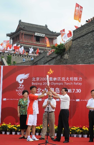 7月30日,在秦皇岛火炬传递的起点老龙头,第一棒火炬手郗恩庭(前左)接过火炬。当日,北京奥运圣火在河北省秦皇岛市传递。 新华社记者巩志宏摄