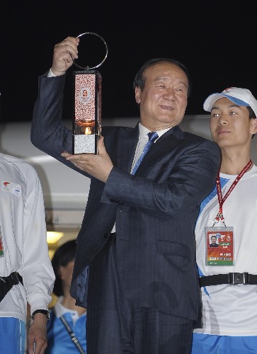 4月18日,北京奥组委执行副主席蒋效愚(中)手捧火种灯走出机舱。新华社记者 戚恒 摄