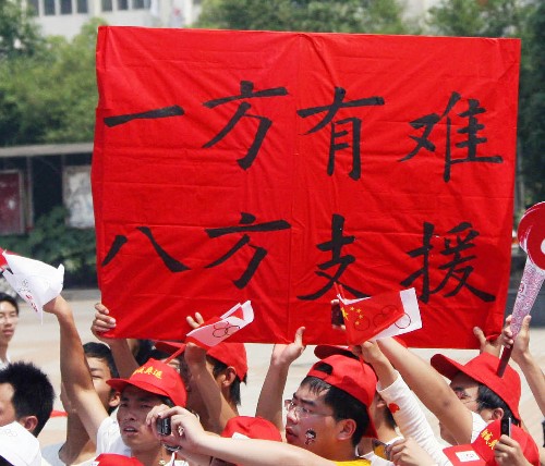 5月16日,当地群众在观看圣火传递时打出标语支持灾区。当日,北京奥运圣火传递活动在江西南昌举行。 新华社记者 李颖 摄