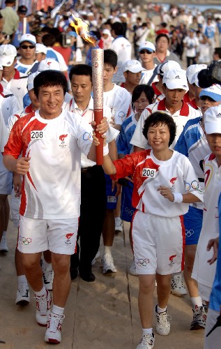 5月4日,最后一棒火炬手成龙(左)和蒲慧芳在天涯海角共同传递火炬。当日,北京奥运会圣火传递活动在海南三亚举行。 新华社记者 赵颖全 摄