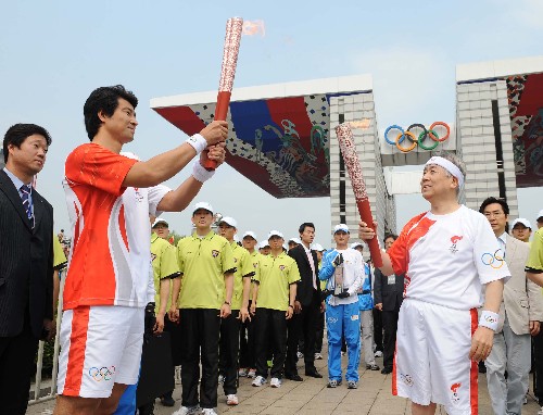 4月27日,奥运火炬手、韩国奥委会主席金正吉(前右)与文大成在传递过程中进行交接。当日,北京奥运圣火传递活动在韩国首尔举行。 新华社记者 安治平 摄