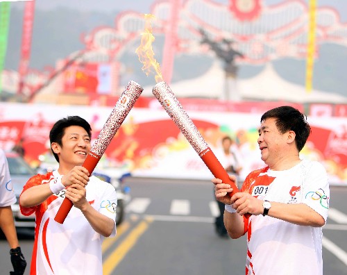 5月25日,火炬手孙志安(右)与火炬手撒贝宁交接。当日,北京奥运会圣火在江苏苏州传递。 新华社记者邢广利摄