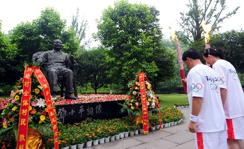 8月3日,火炬手陈静(右)与李良国交接后向邓小平铜像鞠躬。当日,北京奥运圣火在四川省广安市传递。 新华社记者刘力航摄